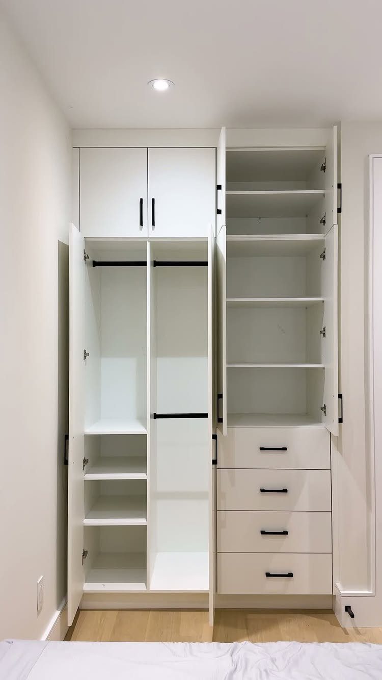 White built-in closet system with cabinets, open shelves, hanging rods, and drawers.