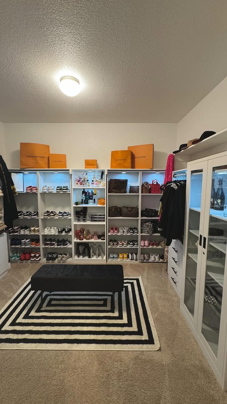 White built-in closet shelves filled with shoes, bags, and orange luxury boxes.