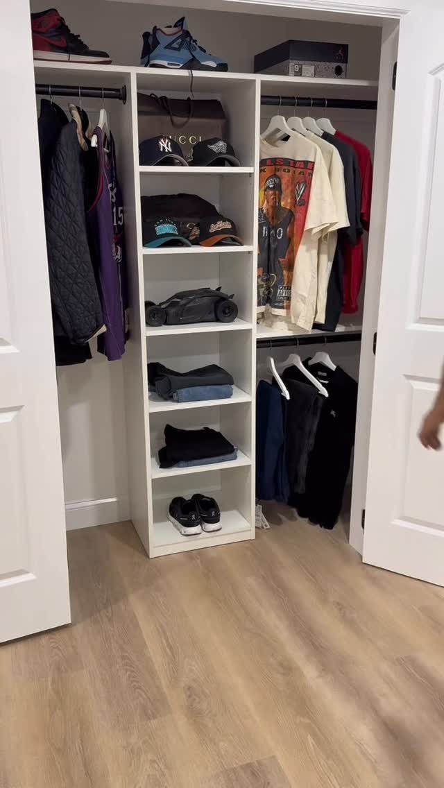 White built-in closet shelving unit with hanging rods containing various clothes and accessories.