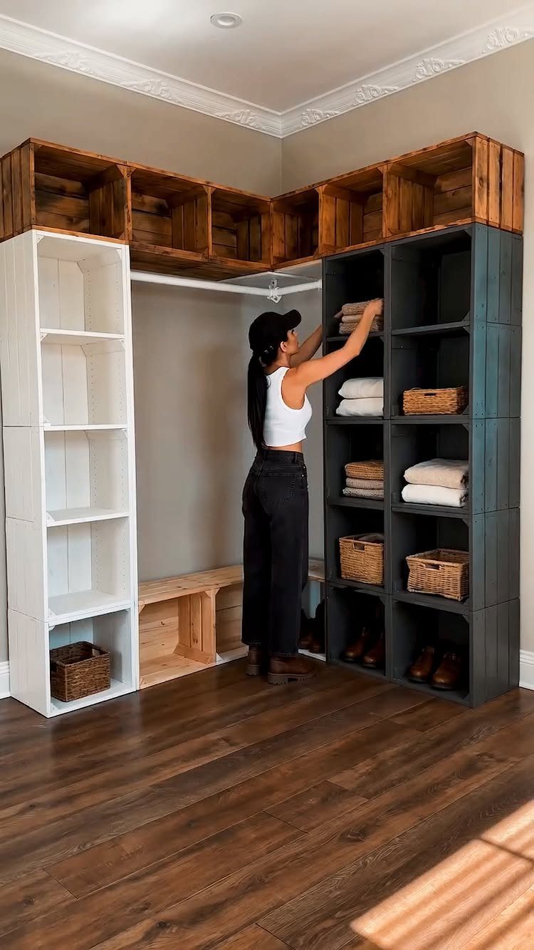 A woman organizing folded linens and baskets on a dark grey floor-mounted shelving unit.