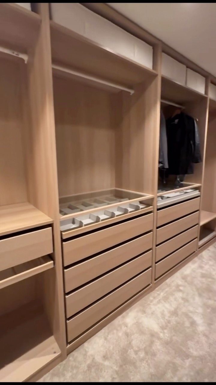 Light wood built-in closet system with drawers and glass-topped accessory organizers.
