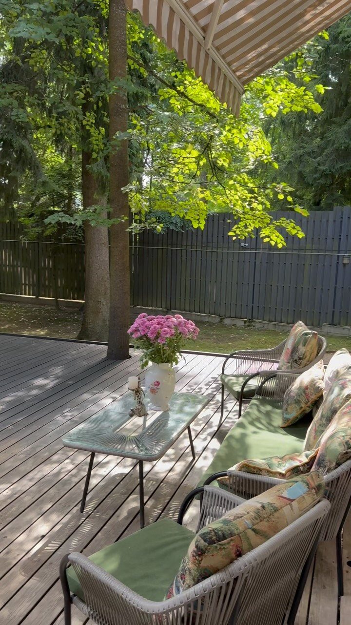 Wicker patio chairs with green cushions and a small glass coffee table on a wooden deck.
