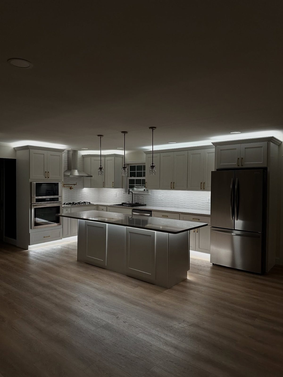 Modern kitchen featuring grey cabinetry with ambient lighting installed above the cabinets and under the island.