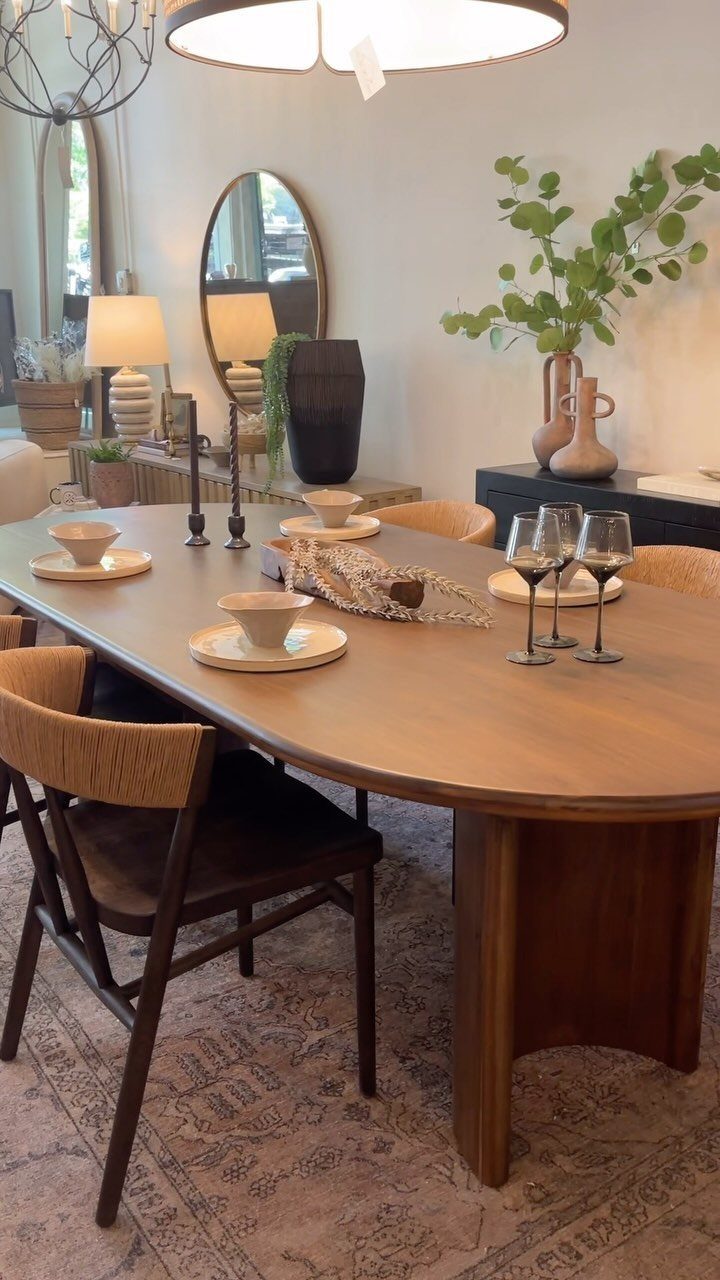 A large wooden oval dining table set with plates and wine glasses in a dining room.