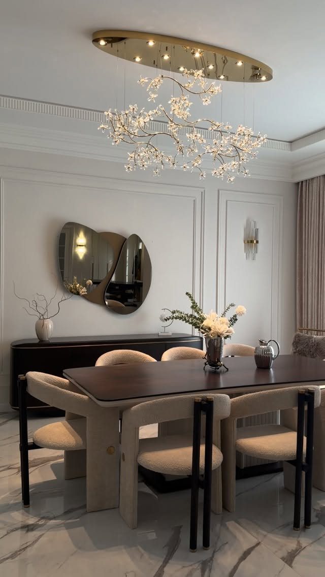 11 Minimalist Dining Room Decor Ideas for Calm, Collected Spaces 10 Minimalist dining room with a dark wood table, cream chairs, and a floral branch chandelier.