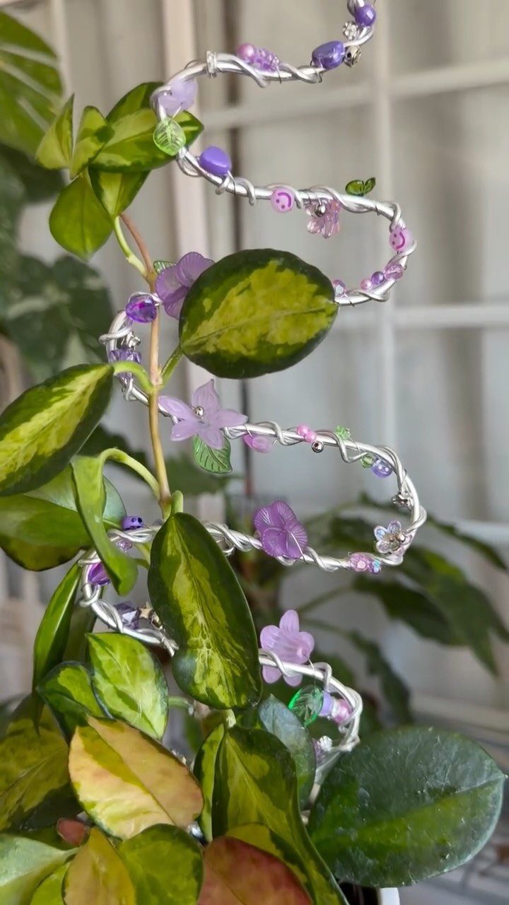 DIY Plant Trellis Indoor: 8 Ideas Using Wood, Rope and Wire 7 A silver wire trellis with purple beads and flowers supporting a green indoor plant.