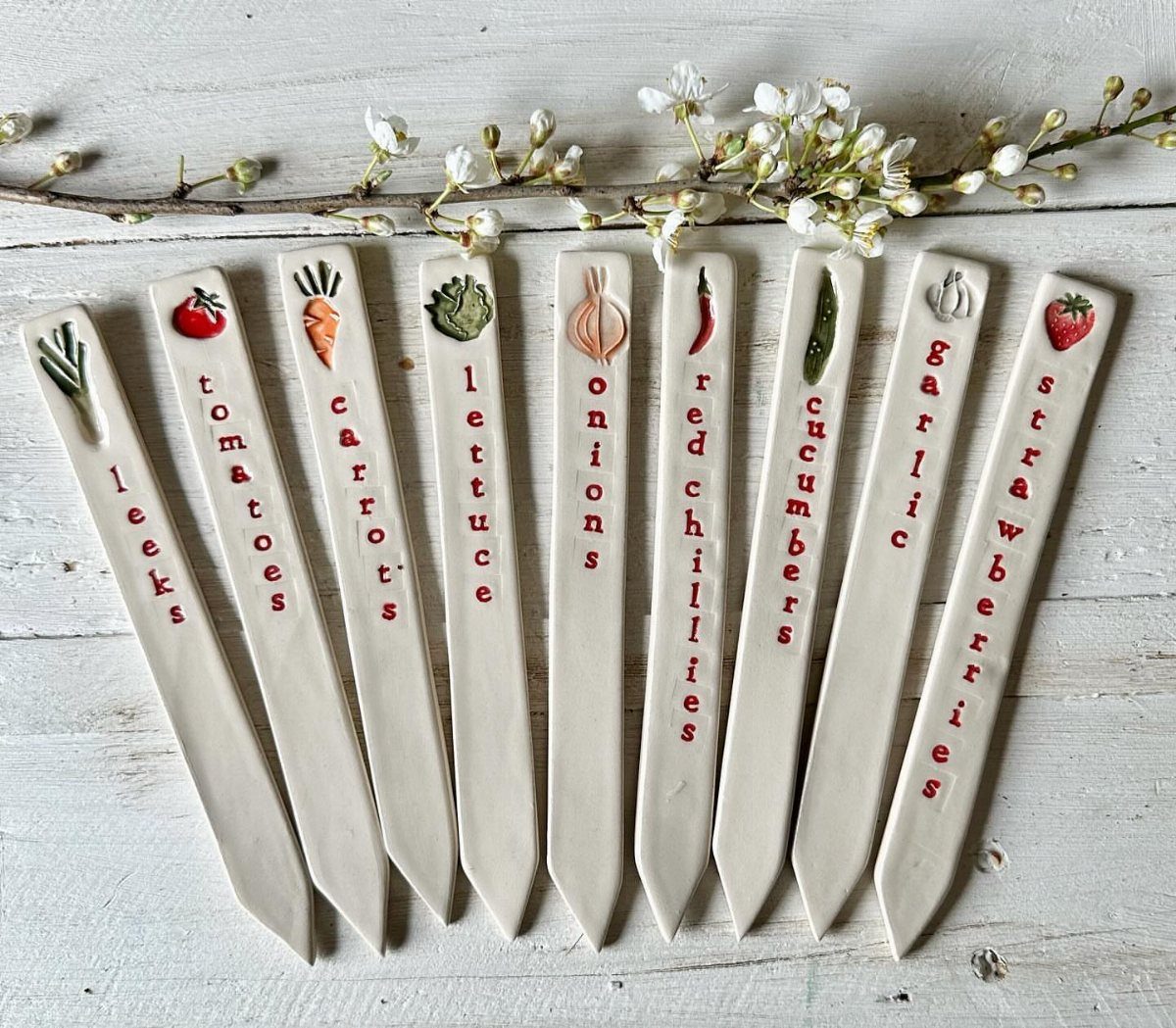 DIY Plants and Decor: 6 Home Projects Worth Making 5 Ceramic plant markers with painted vegetable illustrations and red text arranged on a wooden surface.