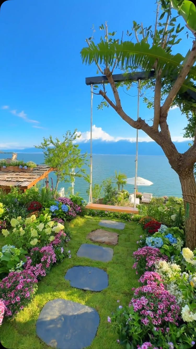 Dream Garden for Your Aesthetic: 20 Ideas to Steal 17 A vibrant garden with stepping stones and a swing overlooking the blue ocean.