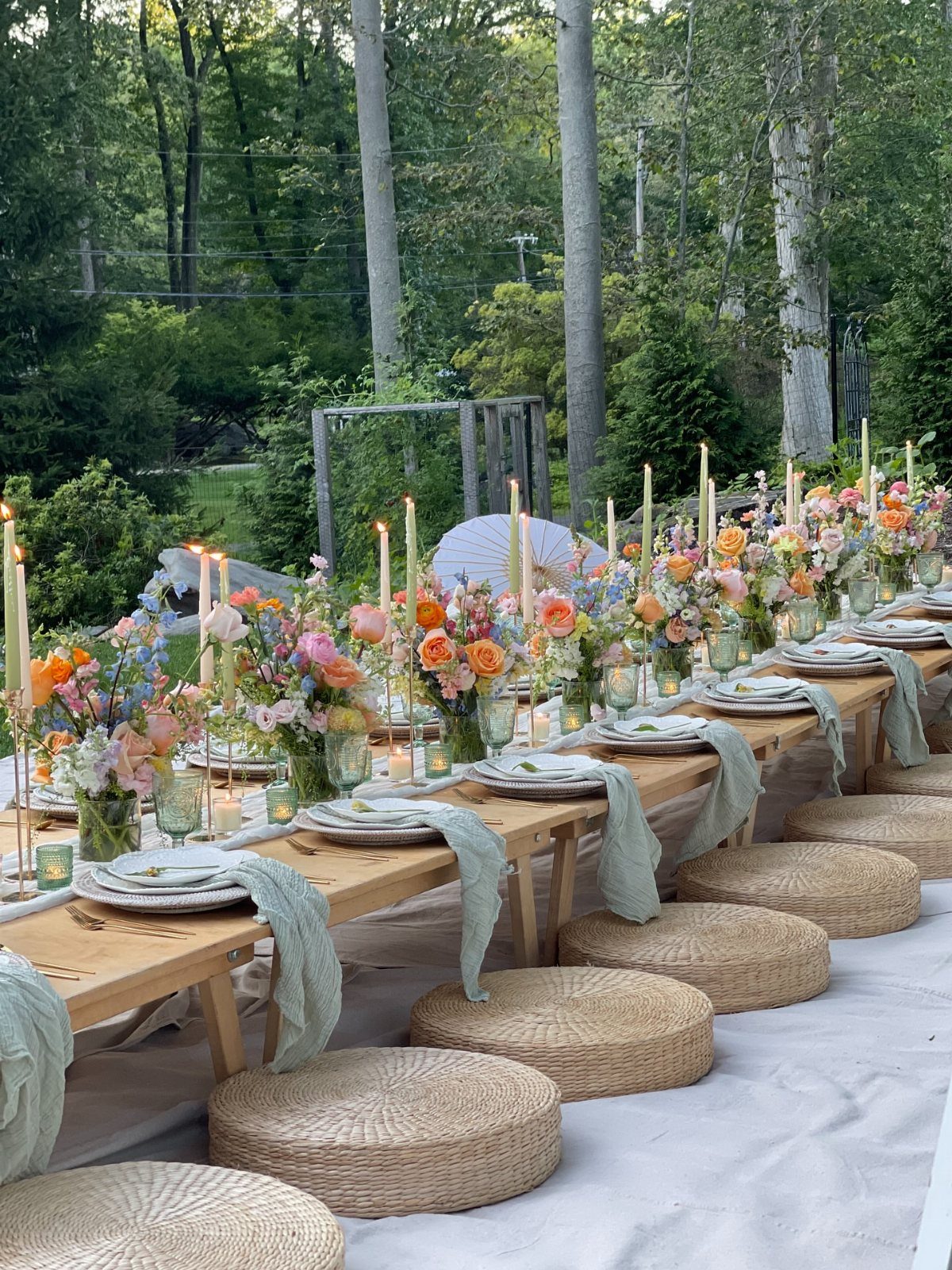 Dream Garden for Your Aesthetic: 20 Ideas to Steal 7 A long wooden table decorated with colorful flowers, candles, and light green napkins for an outdoor garden party.