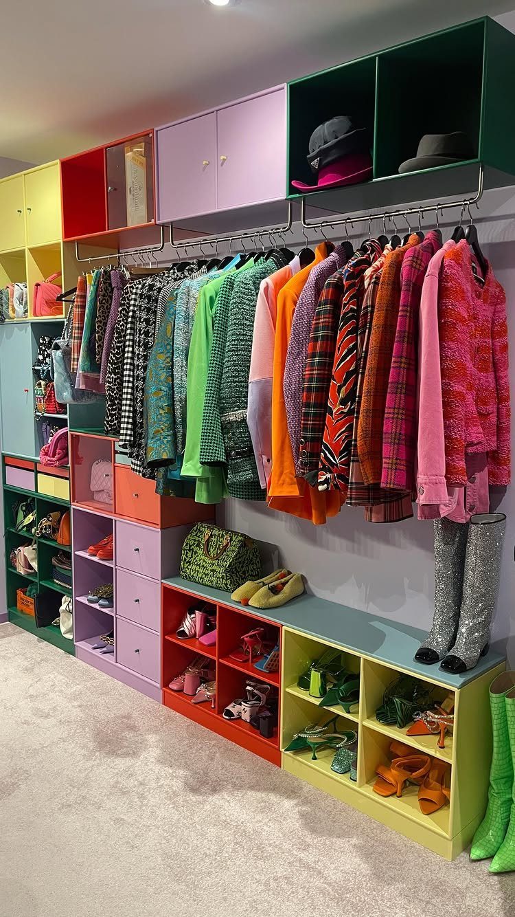 Colorful clothes hanging on a closet rod, organized by color from green to pink.