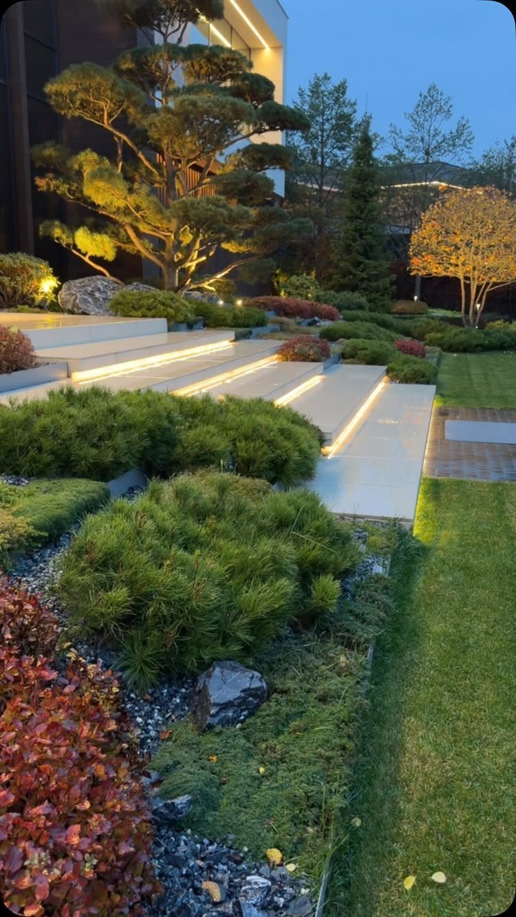 13 Estate Garden Design Ideas With Photos and Planning Tips 9 Manicured estate garden with illuminated stone steps and sculpted ornamental trees at twilight.