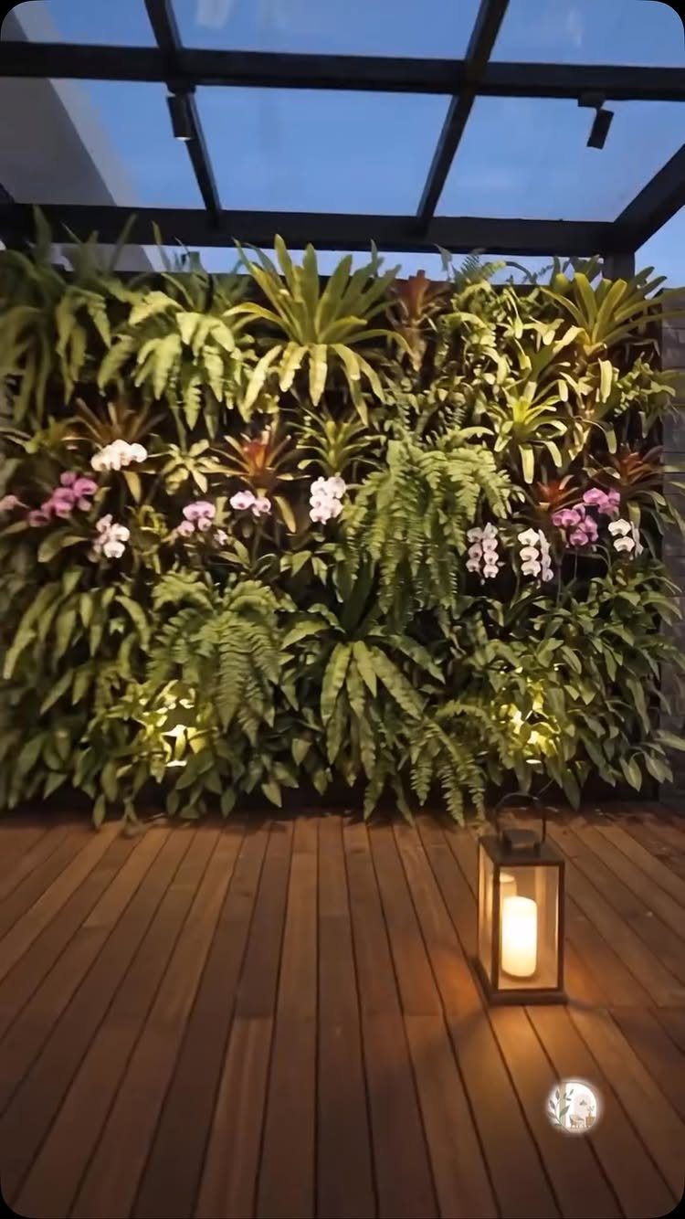 13 Estate Garden Design Ideas With Photos and Planning Tips 4 A lush vertical garden wall featuring green ferns and pink orchids above a wooden deck.