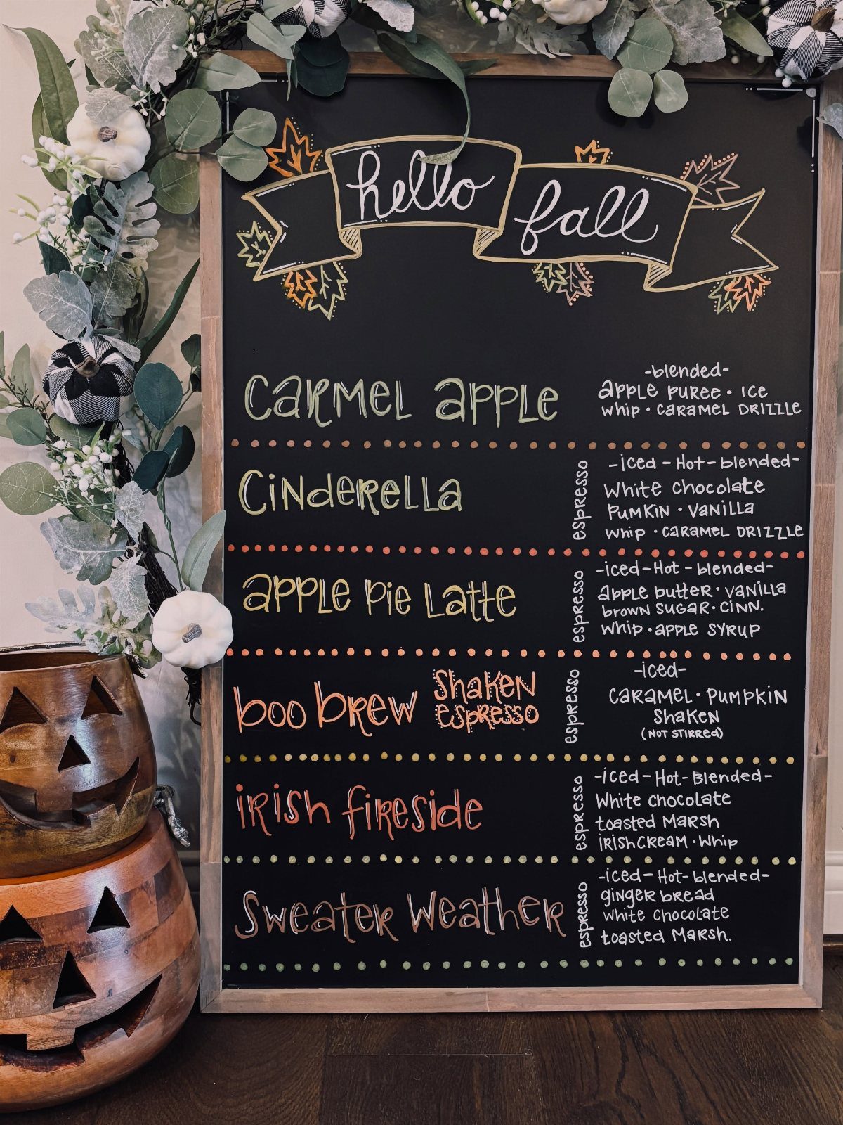 16 Farmhouse Coffee Bar Ideas for Pantry Nooks to Pallet Walls 8 A chalkboard menu with fall-themed coffee drink names decorated with autumn leaves and greenery.