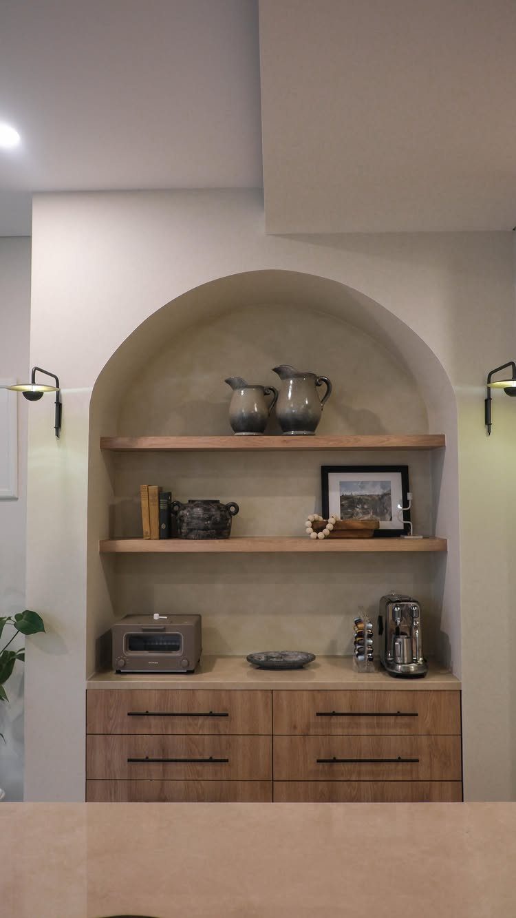 16 Farmhouse Coffee Bar Ideas for Pantry Nooks to Pallet Walls 7 An arched alcove with wooden floating shelves and a matching wood countertop containing various kitchen items.