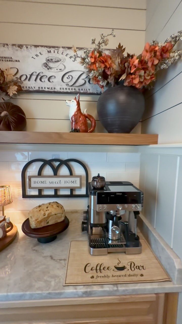 16 Farmhouse Coffee Bar Ideas for Pantry Nooks to Pallet Walls 15 Espresso machine and coffee bar decor on a marble countertop with autumn leaves and fox figurine.
