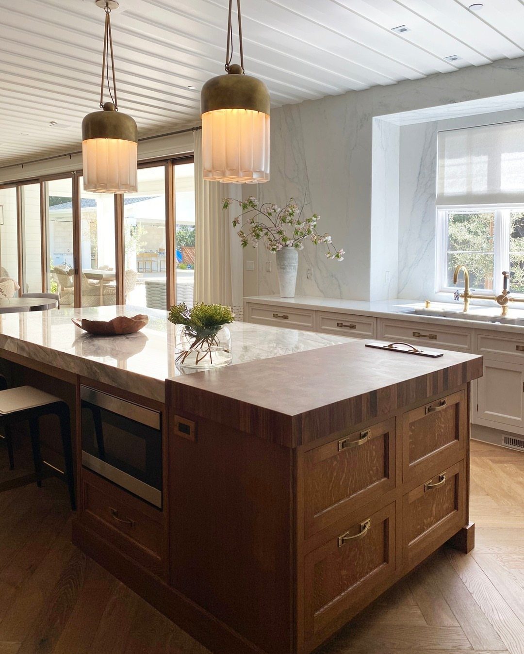 A large kitchen island with a thick butcher block wooden countertop and marble surface.