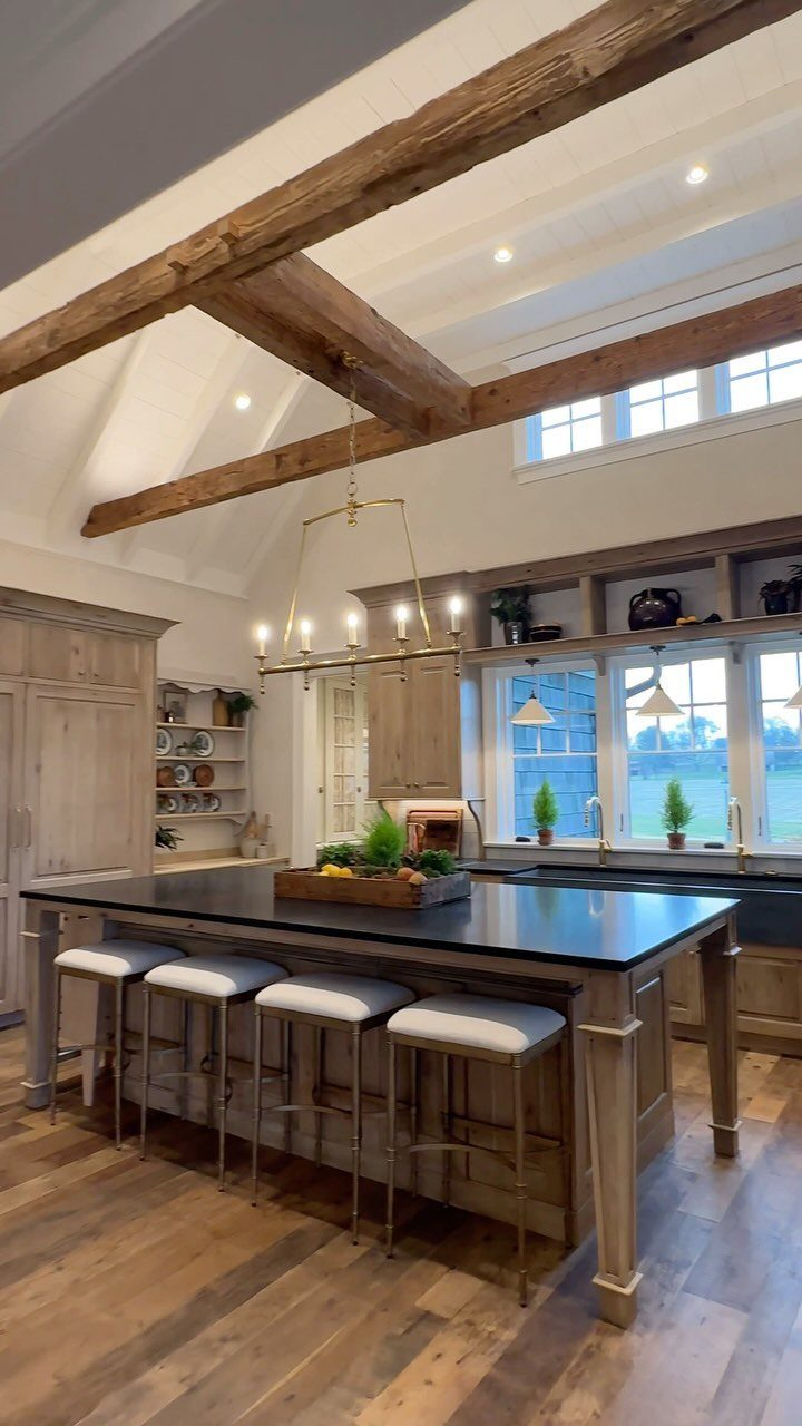 Rustic wooden cabinets and island in a bright kitchen with exposed ceiling beams.