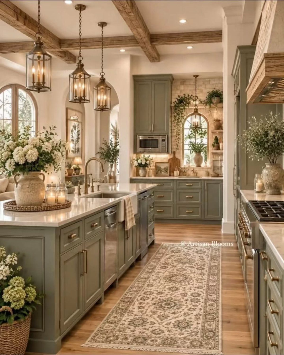 Sage green kitchen cabinets with white marble countertops and rustic wooden ceiling beams.