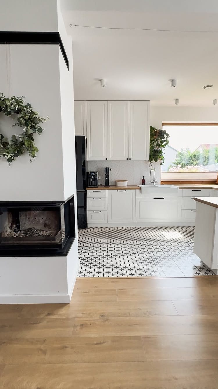 A bright kitchen featuring white cabinets and a black and white patterned tile floor.