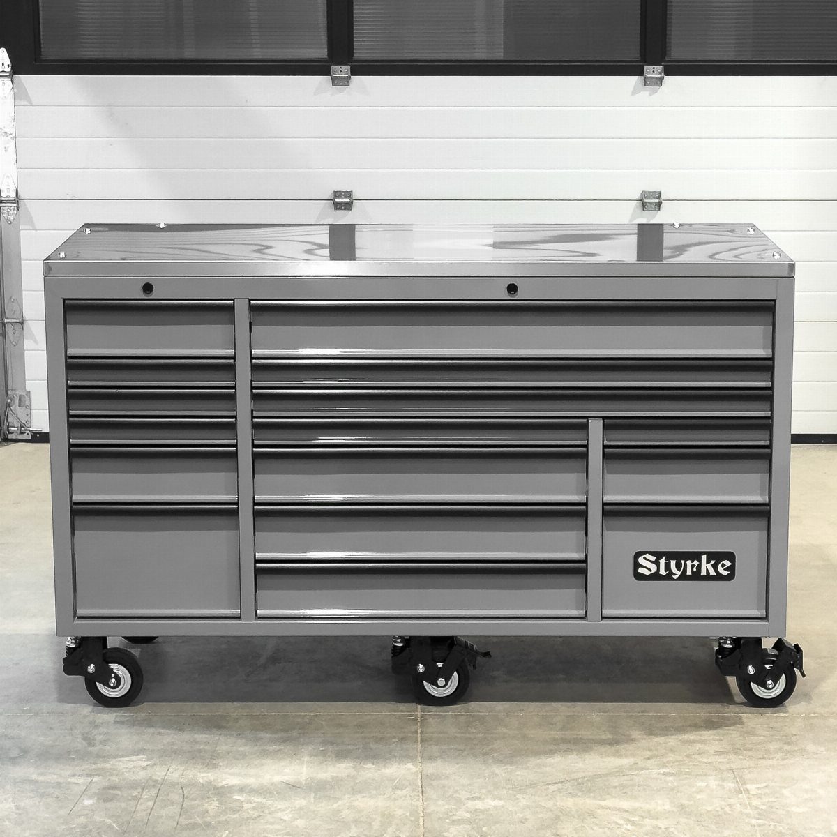A large grey metal rolling tool chest with multiple drawers on wheels in a garage.