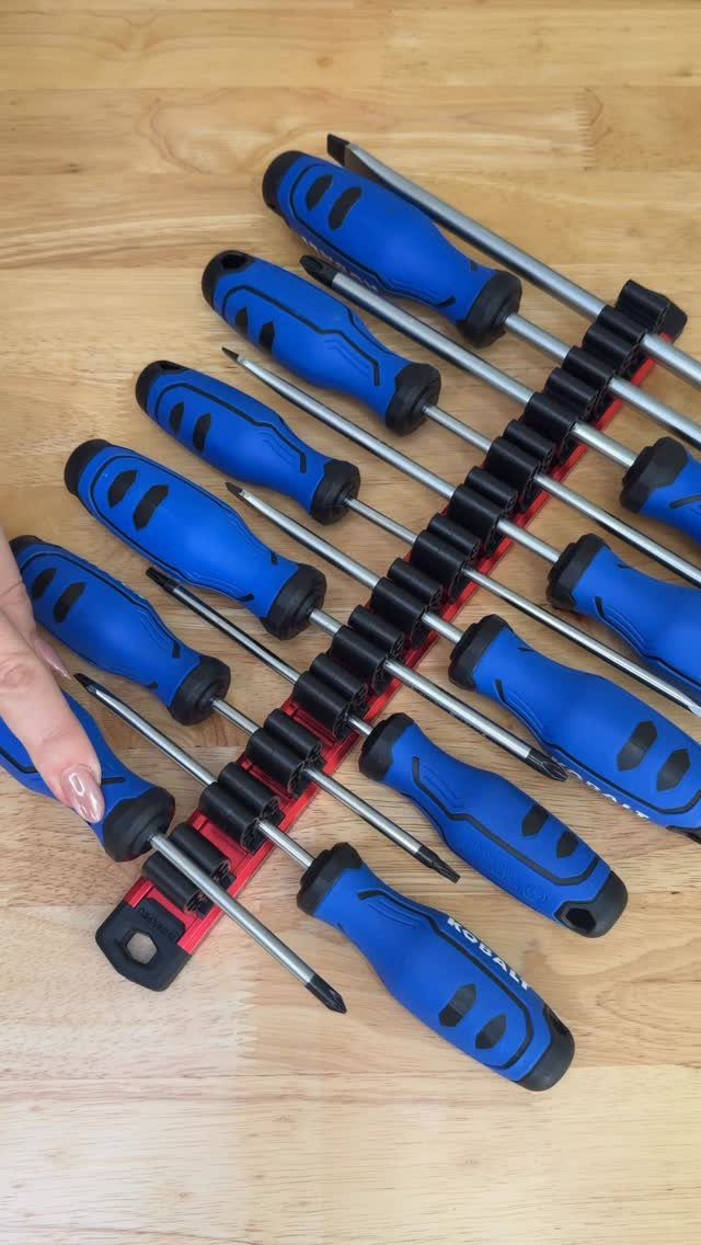 Blue-handled screwdrivers being placed into a black and red plastic tool organizer strip.