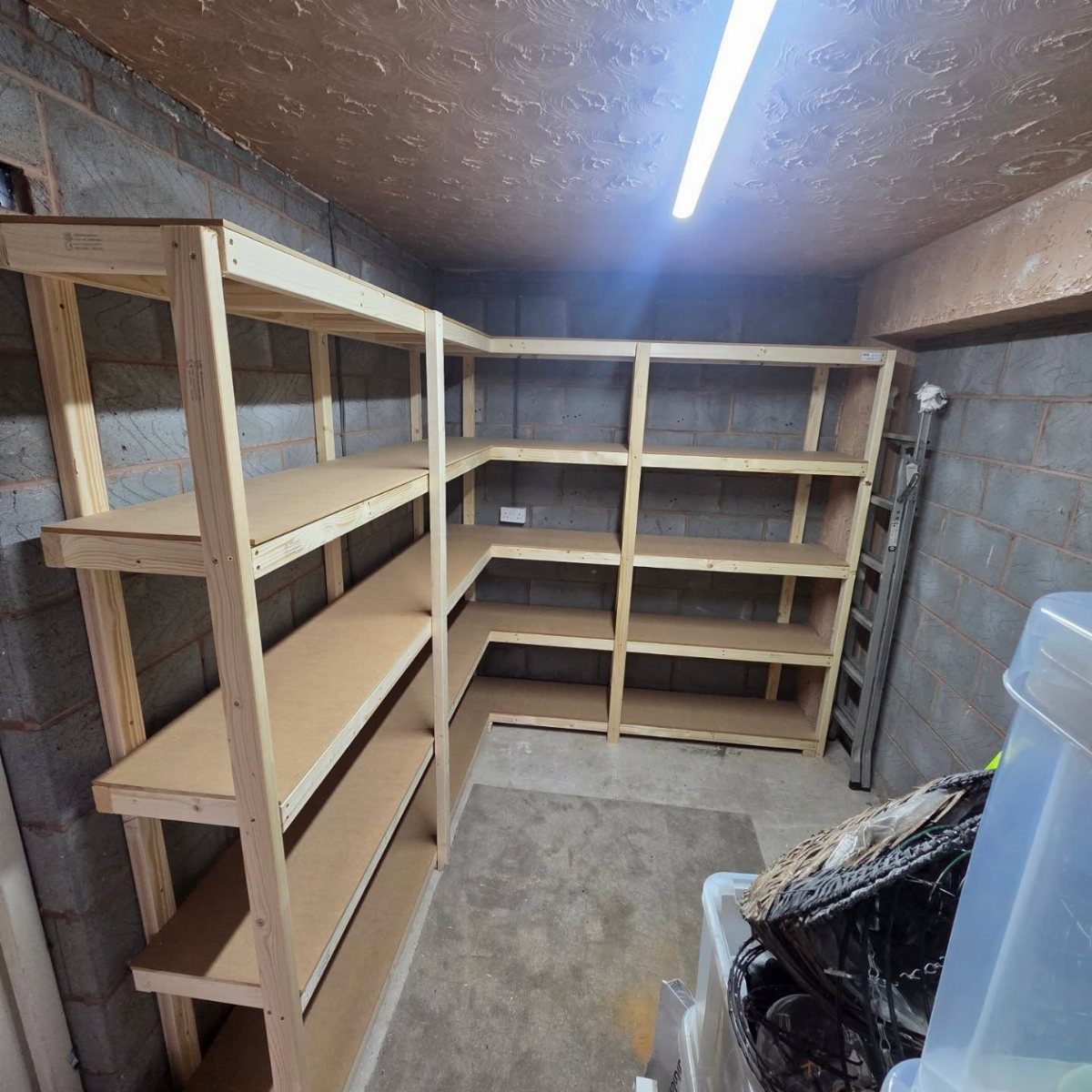 Garage Storage and Workshop: 8 Ideas That Actually Fit 4 Wooden L-shaped shelving units installed against grey cinder block walls in a garage corner.