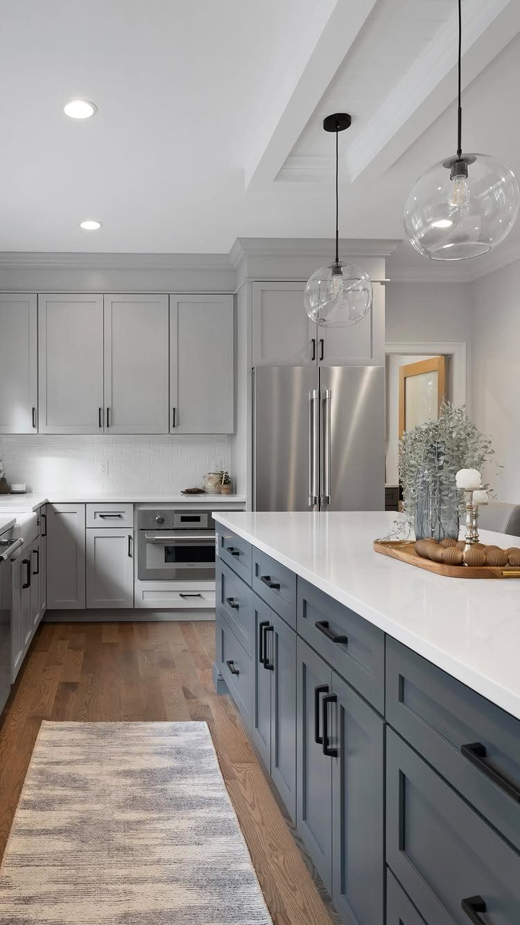 Modern kitchen with light grey upper cabinets and a large navy blue island with white countertops.