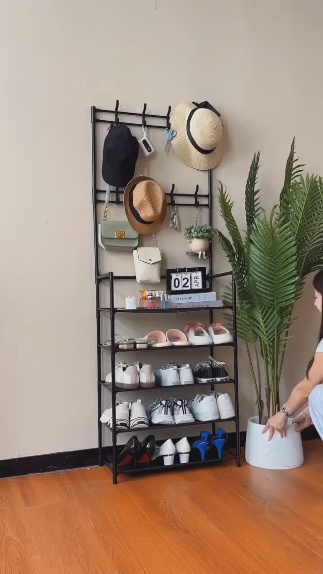 Black metal multi-tier rack holding hats, a small handbag, and several pairs of shoes.