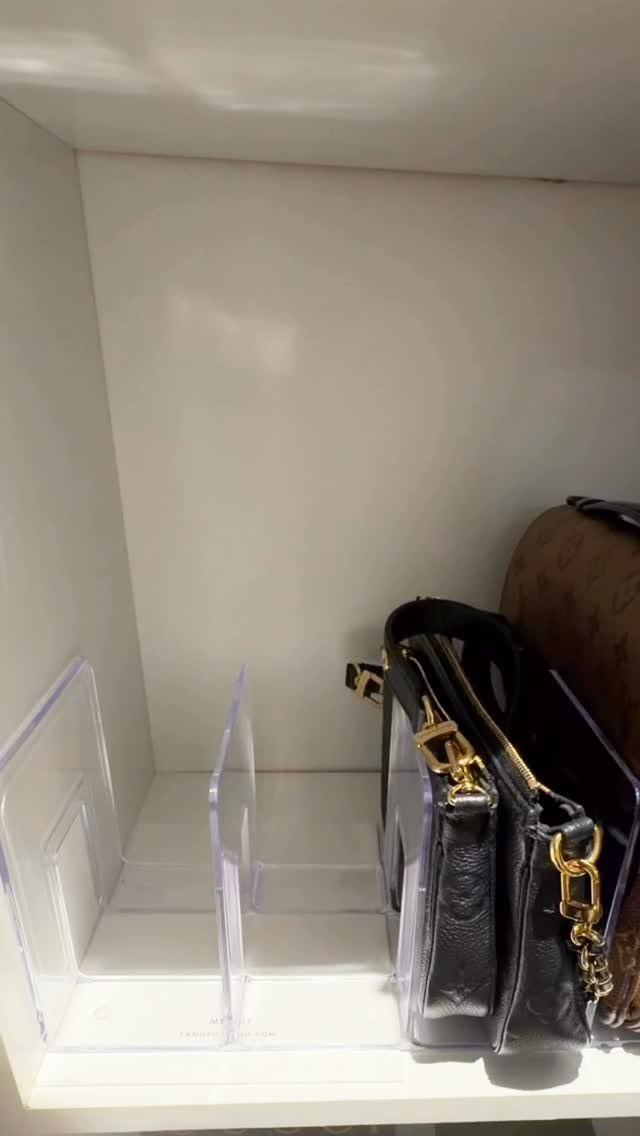 Clear acrylic letter holders placed on a white shelf next to a black handbag.