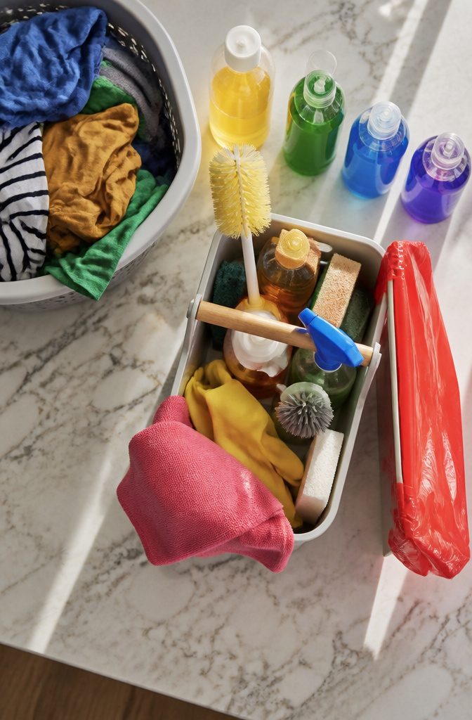 How to Clean the Room: 8 Steps for a Fresh Space 1 A cleaning caddy with a trash bag, laundry basket, and microfiber cloths.