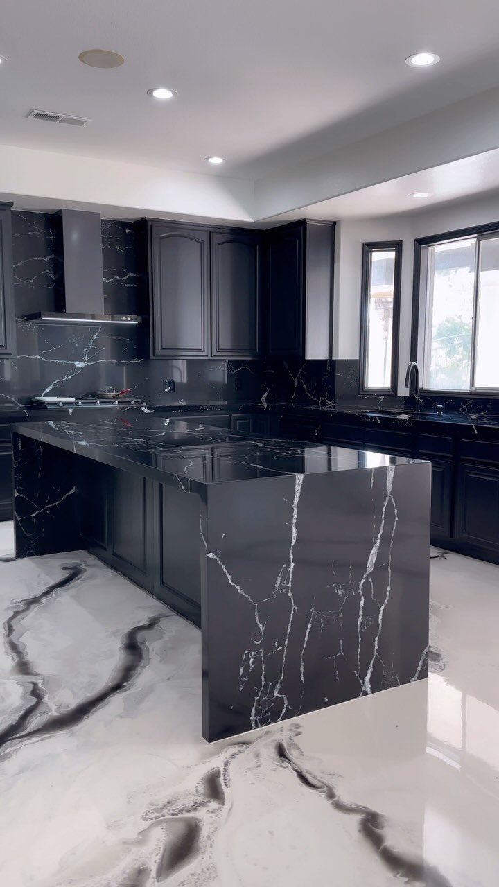 Black marble-patterned kitchen island and countertops with white veining in a modern kitchen.