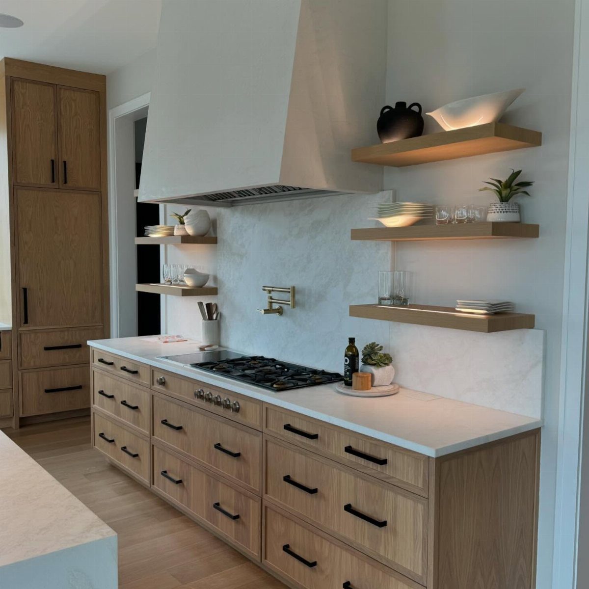 Modern kitchen with light wood cabinets, marble countertops, and floating wooden open shelves.