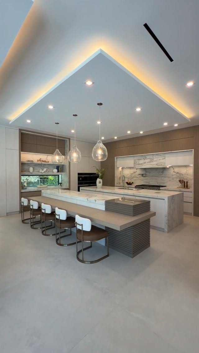 Modern kitchen island with a wooden breakfast bar, stone countertop, and three glass pendant lights.