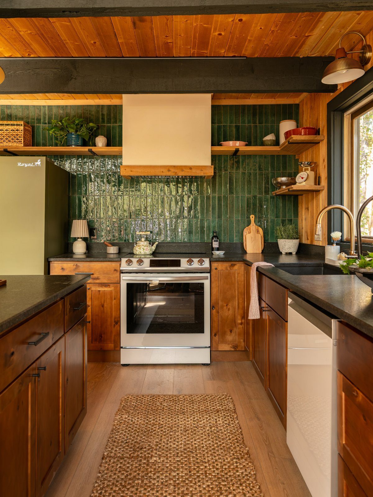 Dark wood ceiling beams over a rustic kitchen with green tiles and wooden cabinetry.
