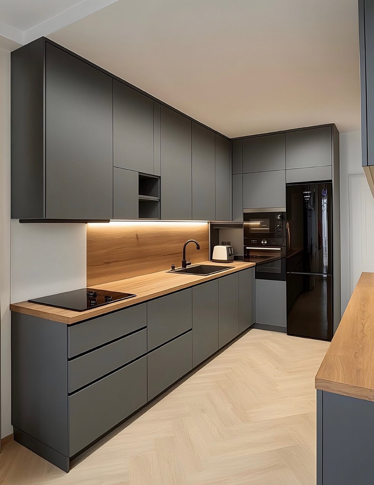 Light wood herringbone flooring in a modern kitchen with dark grey cabinetry and wooden countertops.