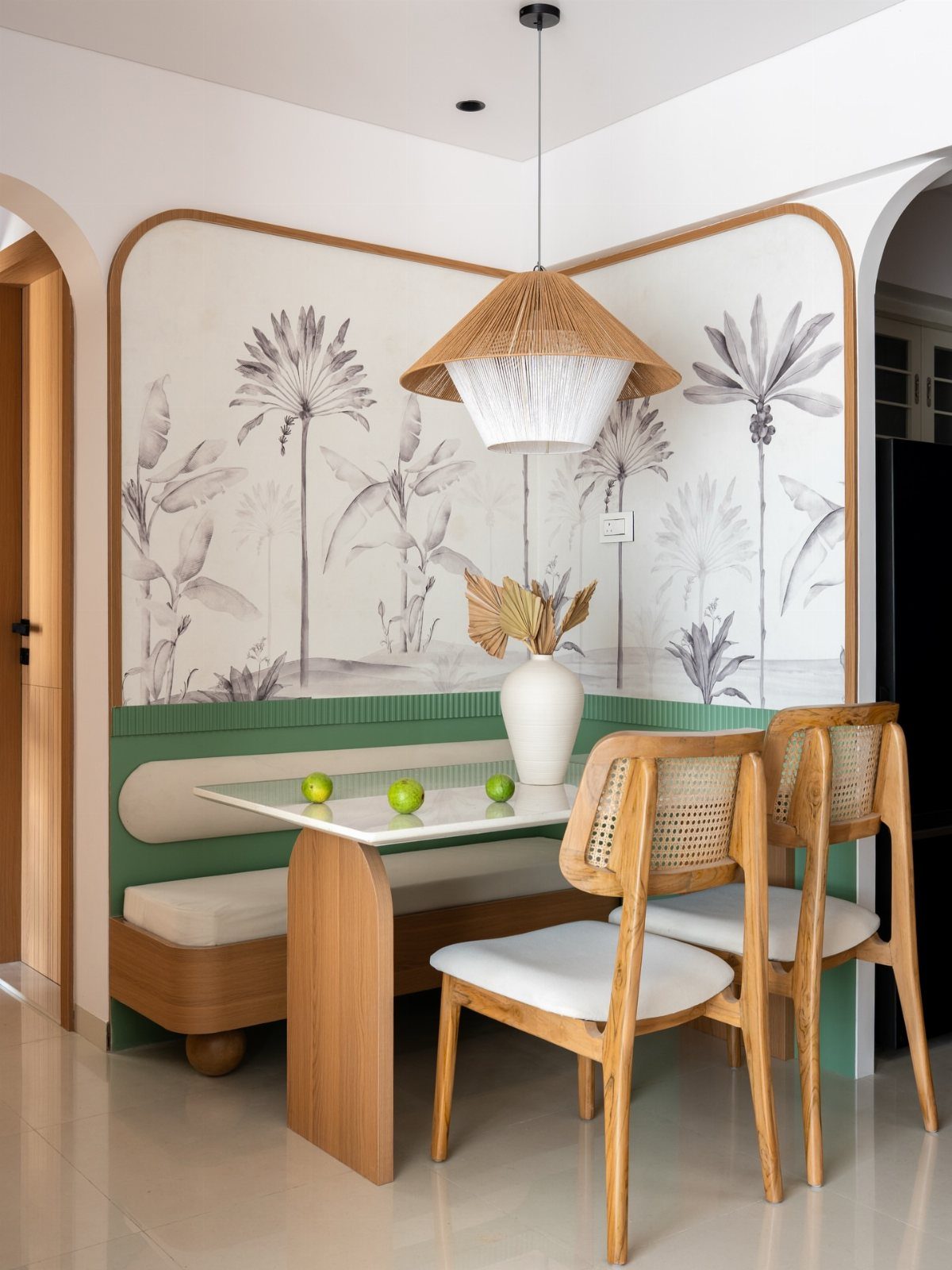 Corner dining banquette with cream cushions, marble table, and woven pendant light in a botanical nook.