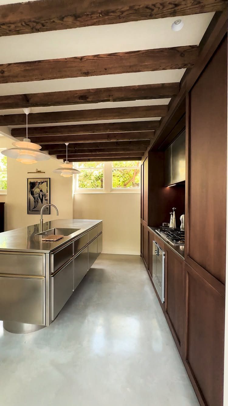 Dark wooden exposed beams running across a white ceiling in a modern kitchen.