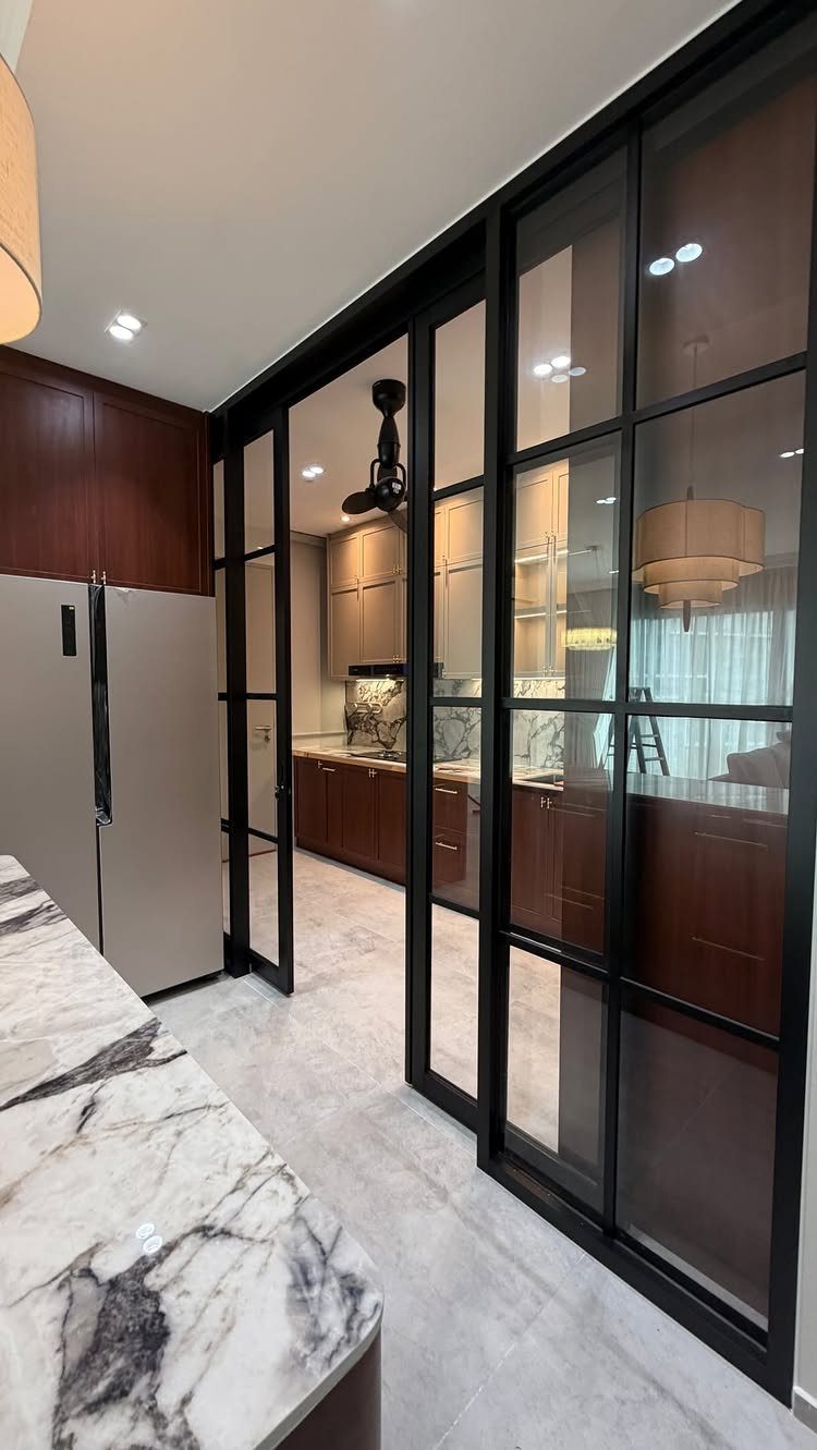 Black-framed glass sliding doors separating a modern kitchen from an adjacent living space.