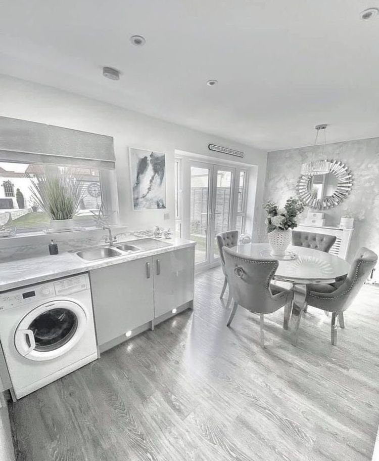 Round marble dining table with grey upholstered chairs in a bright, modern kitchen setting.