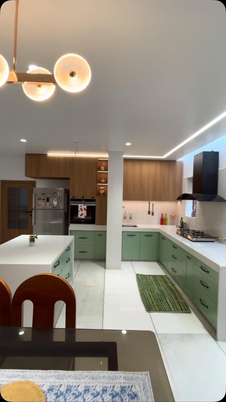 Sage green kitchen cabinets paired with white countertops and light wood upper cabinetry.
