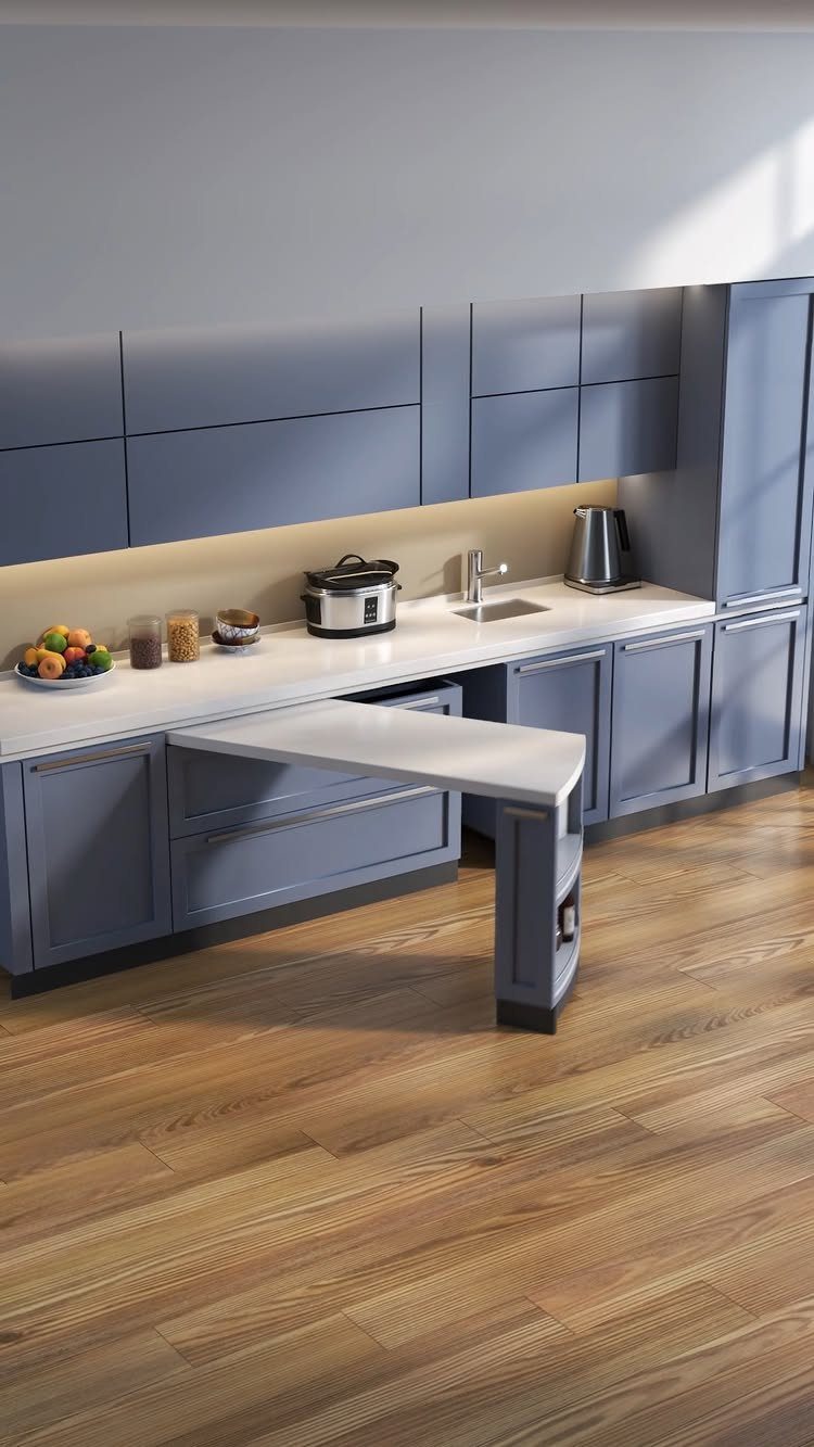 Blue kitchen cabinets with a white pull-out table extending over light wood flooring.