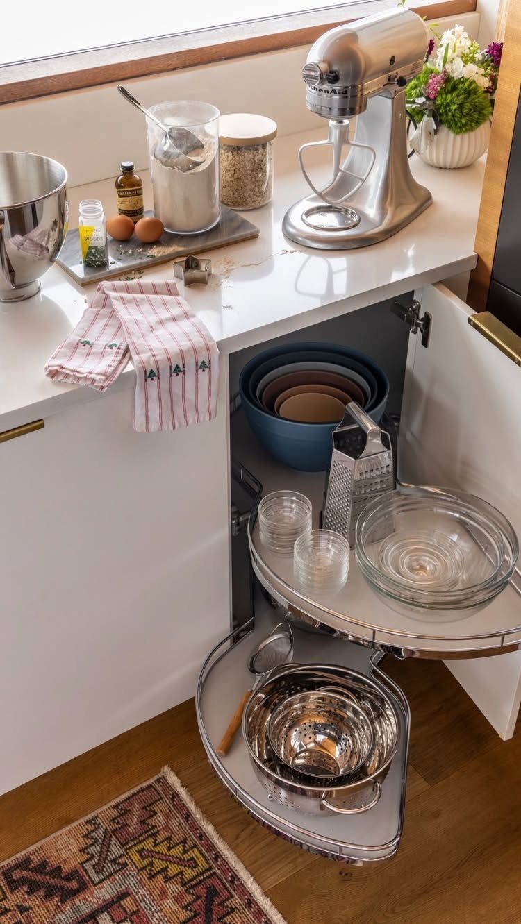 13 Kitchen Organization Ideas for Small Spaces That Free Up Real Room 4 A rotating Lazy Susan inside an open white kitchen cabinet holding bowls and kitchen tools.