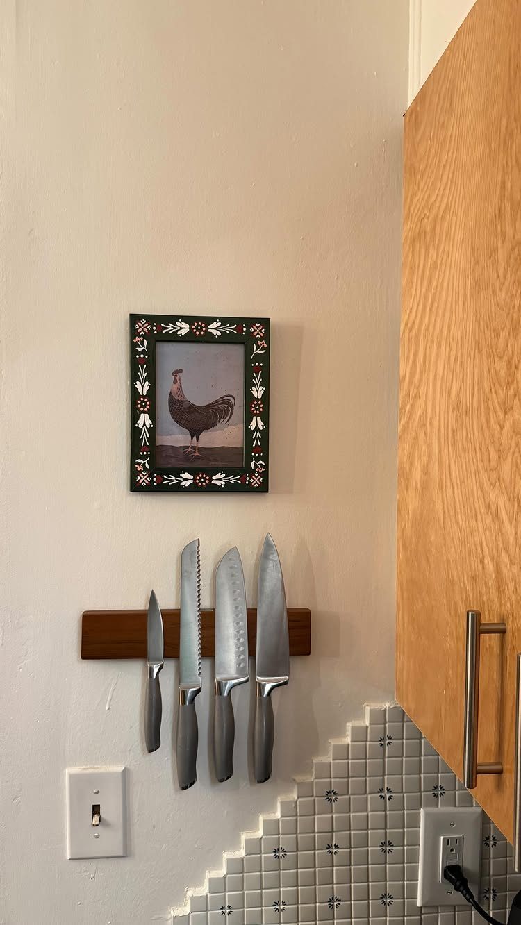 13 Kitchen Organization Ideas for Small Spaces That Free Up Real Room 12 Five stainless steel kitchen knives hanging from a wooden magnetic strip on a white wall.