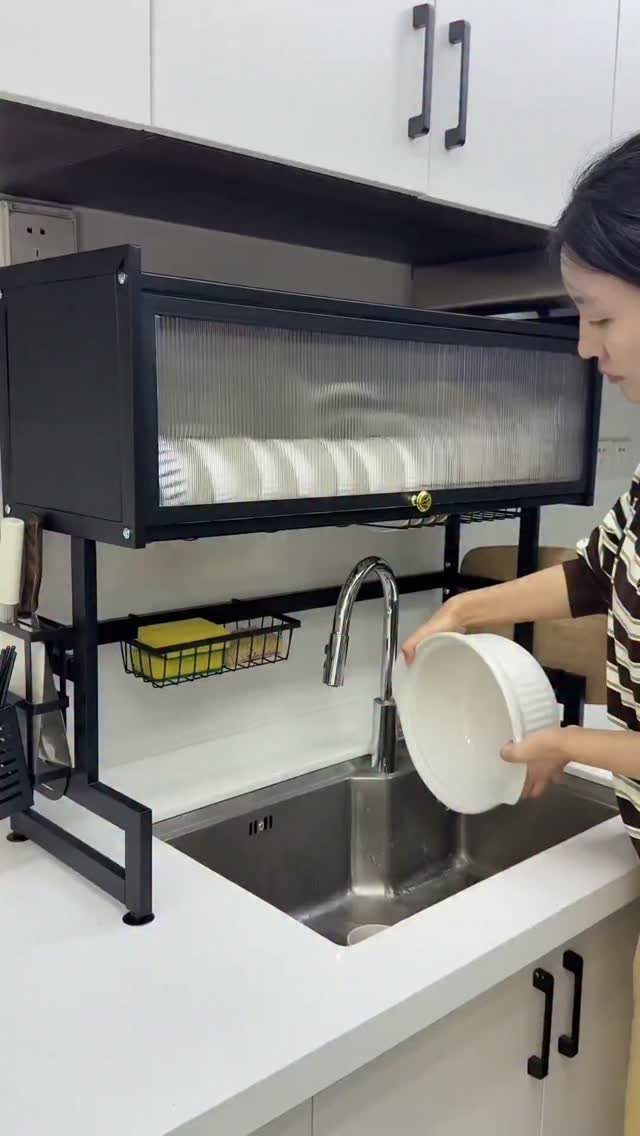 13 Kitchen Organization Ideas for Small Spaces That Free Up Real Room 6 A person holding a white bowl over a sink with a black over-sink dish drying rack above.
