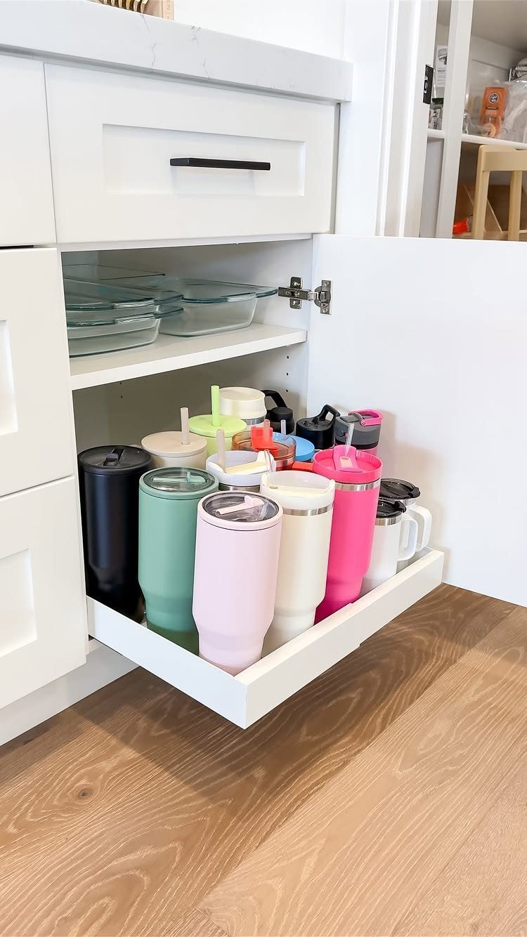 13 Kitchen Organization Ideas for Small Spaces That Free Up Real Room 11 A white pull-out kitchen drawer filled with various colorful insulated tumblers and mugs.
