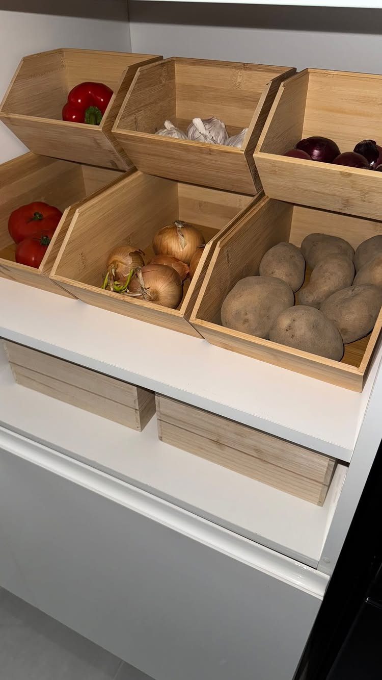 13 Kitchen Organization Ideas for Small Spaces That Free Up Real Room 5 Wooden bins containing potatoes, onions, and peppers stacked on a white kitchen counter.
