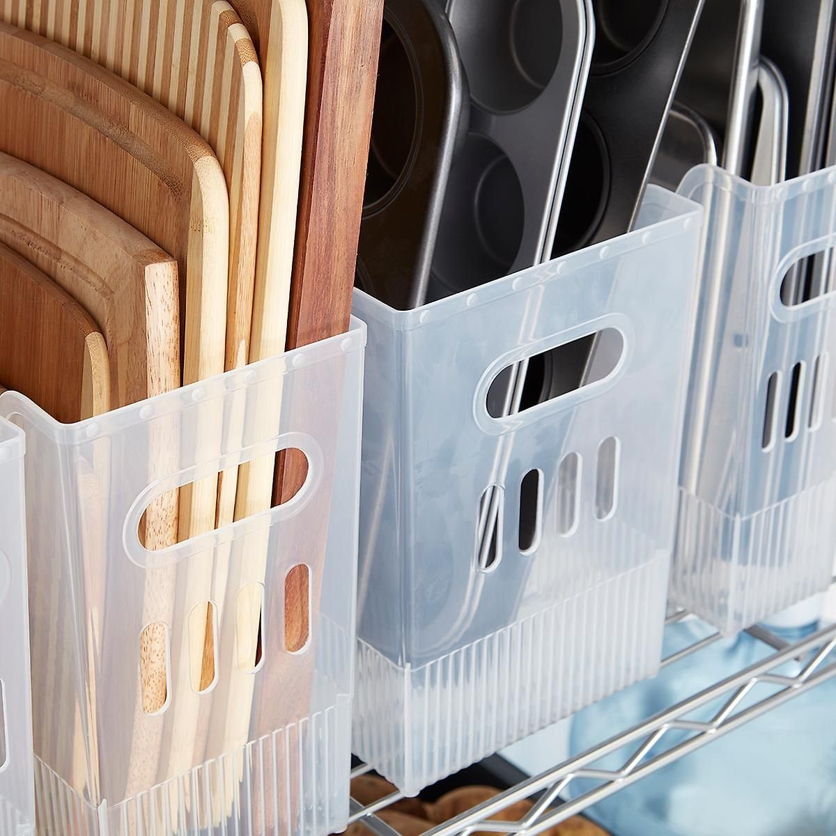 7 Kitchen Storage Tray Ideas for Cabinets and Drawers 5 Translucent plastic storage bins holding wooden cutting boards and dark kitchen containers on a wire shelf.