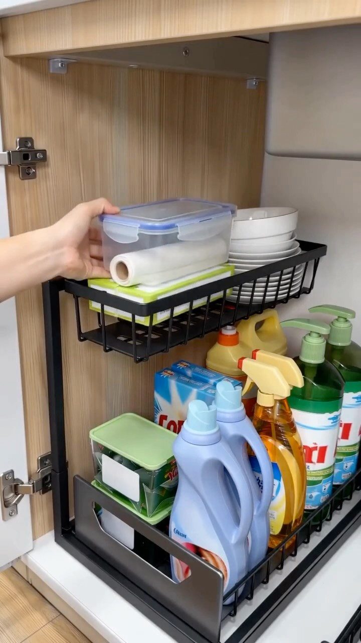 7 Kitchen Storage Tray Ideas for Cabinets and Drawers 3 A hand reaches into a kitchen cabinet to retrieve a container from a black wire pull-out tray.