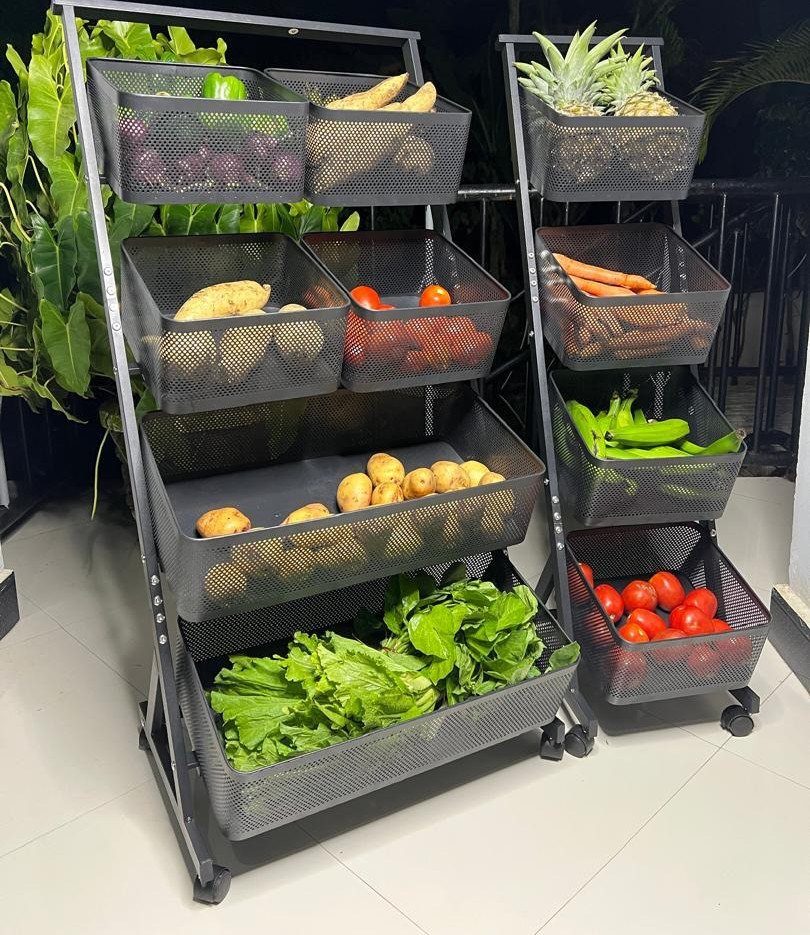 7 Kitchen Storage Tray Ideas for Cabinets and Drawers 2 Two black metal tiered storage racks filled with various fresh vegetables on a tiled floor.