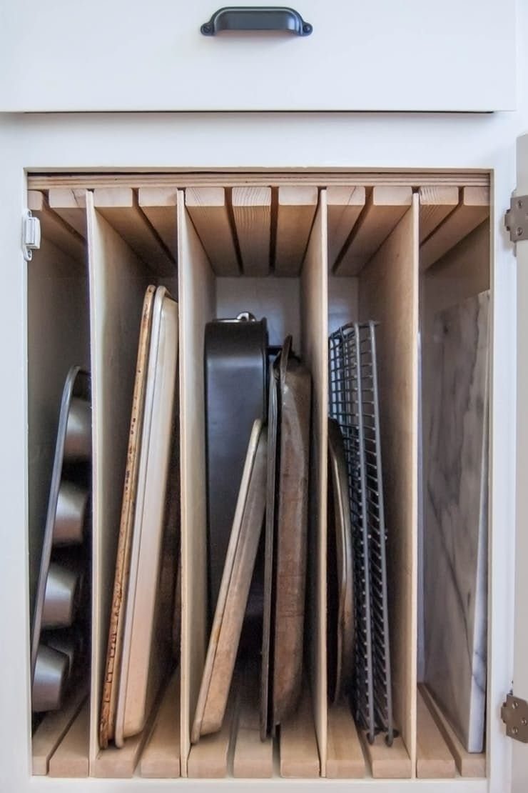 7 Kitchen Storage Tray Ideas for Cabinets and Drawers 1 Vertical wooden dividers inside an open white kitchen drawer organizing various metal baking trays.